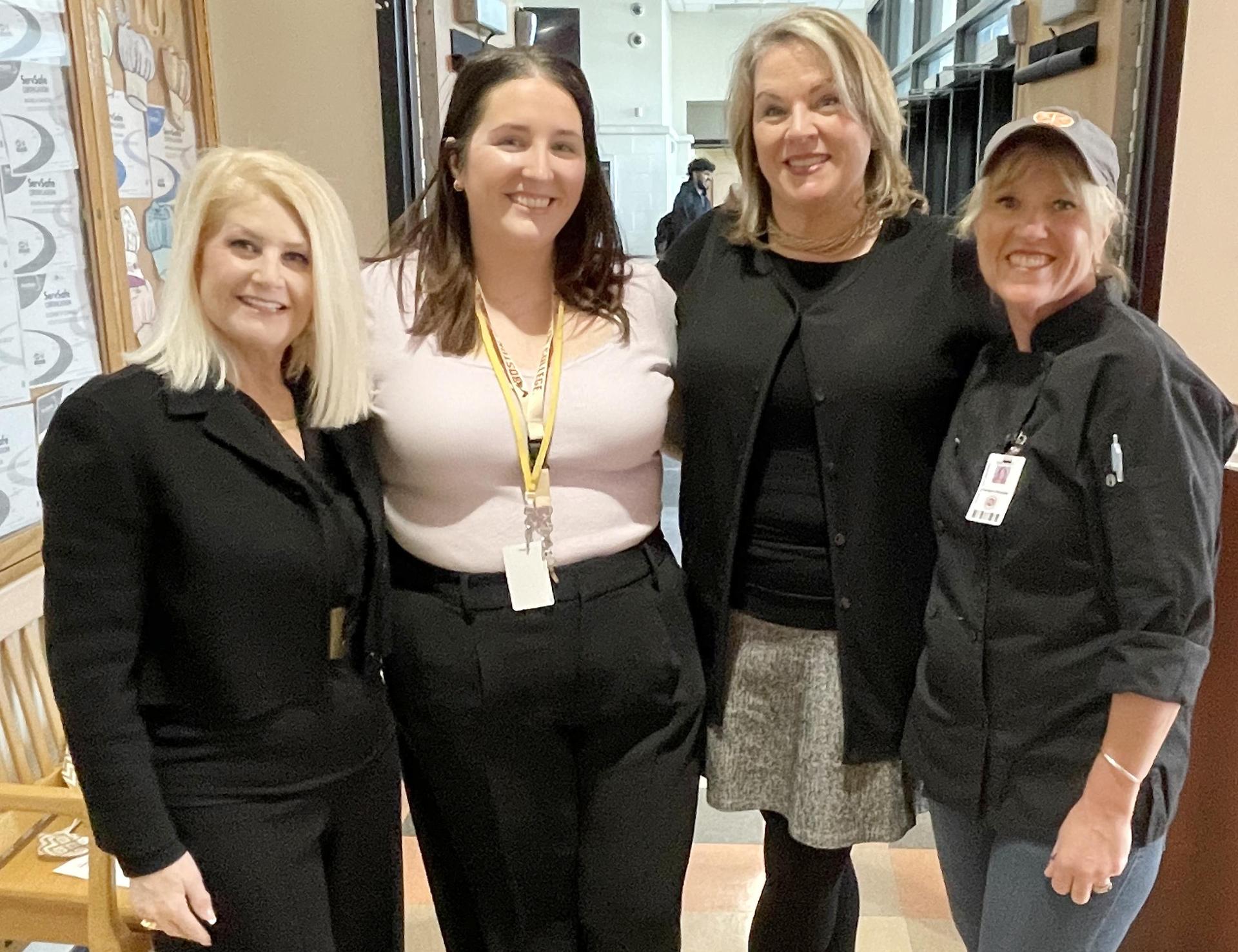 Four women standing, smiling, posed photo
