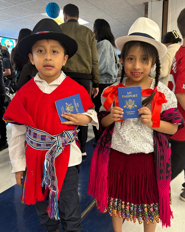 Students dressed in cultural clothing stand with passports