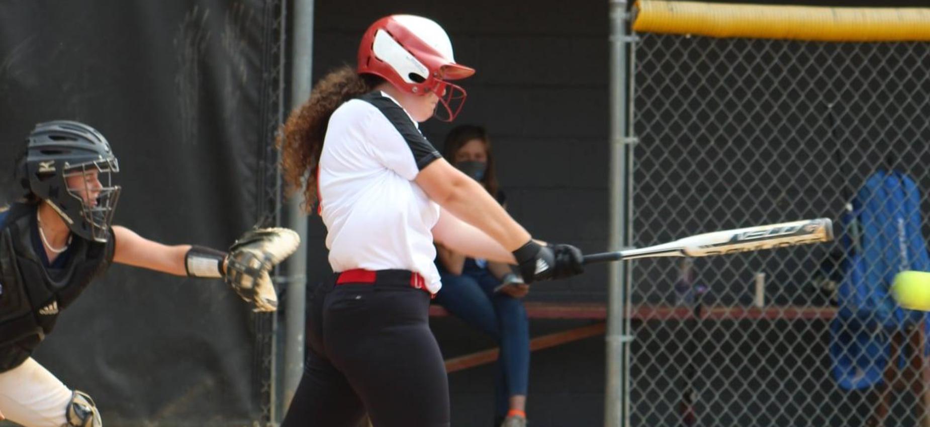 A softball player hits the ball.