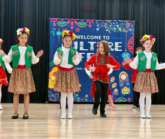 Students in traditional Russian outfits performing on stage