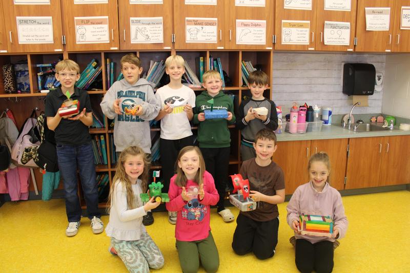 2nd grade students holding boats they created