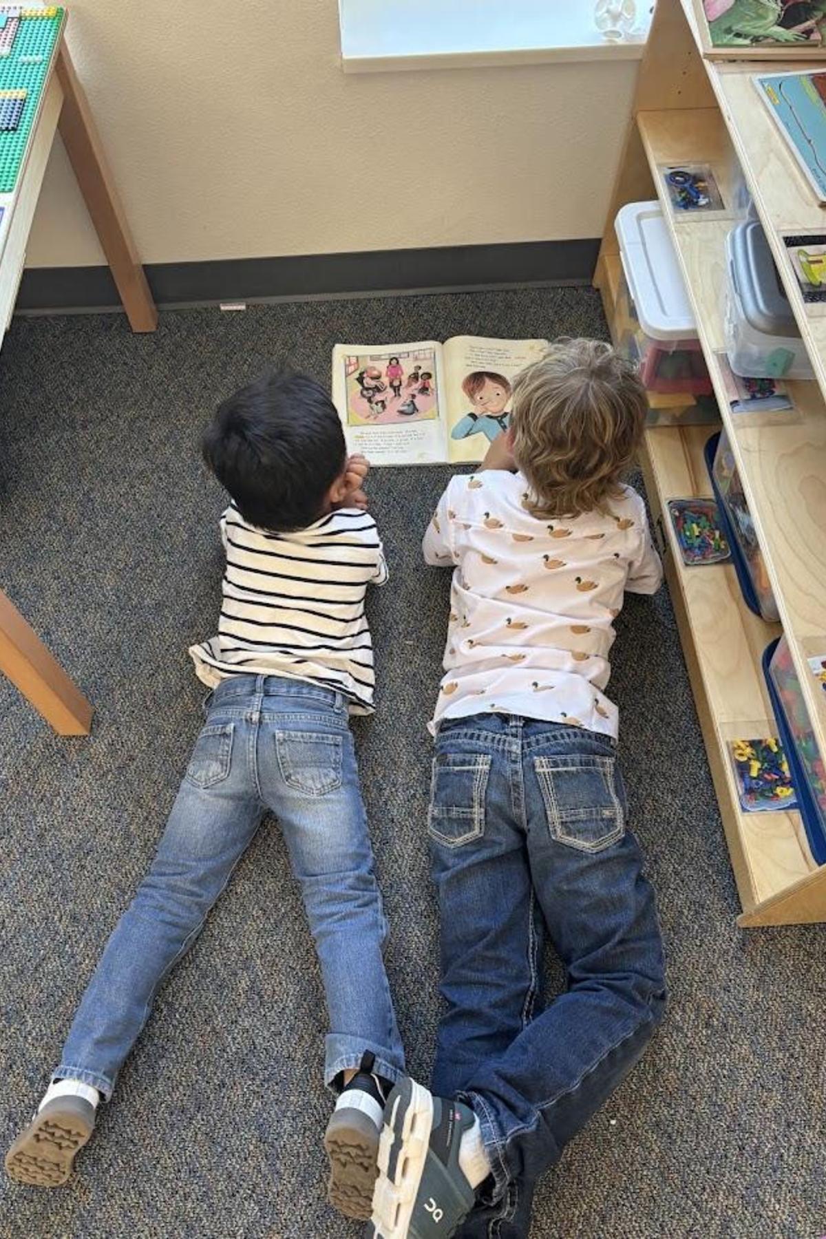 Second grade student reading to preschool student