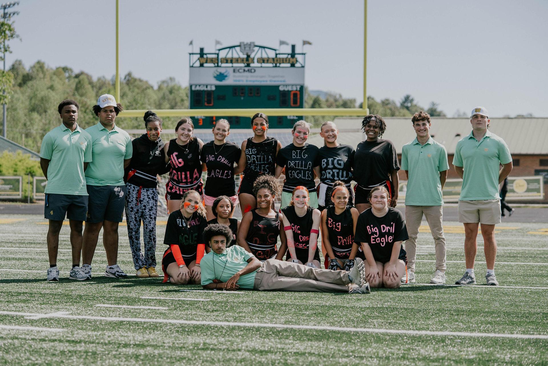 A group of students posed on a sports field, wearing team shirts and showing school spirit.