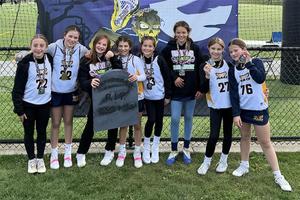 A group of girls wearing white lacrosse jerseys