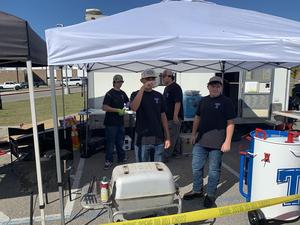 Pitmasters team members talk near the grill during Saturday's cookoff