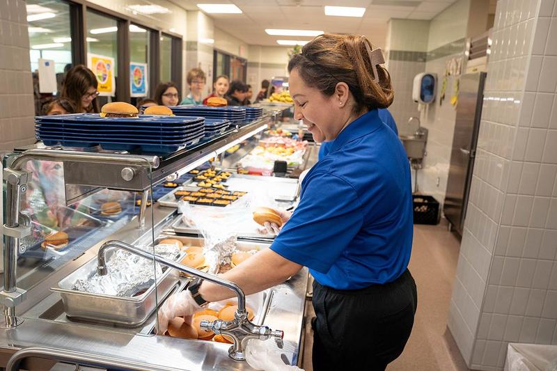 A cafeteria worker serves students