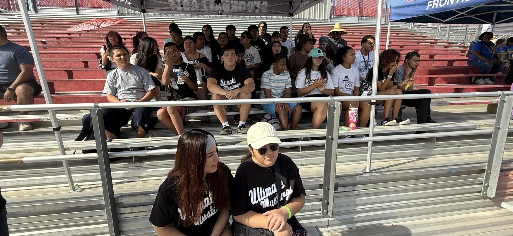 View of a crowd sitting in bleachers at an outdoor event.