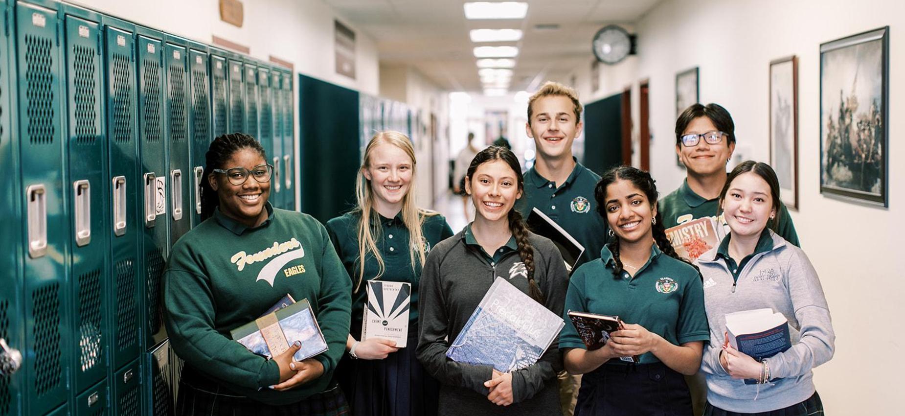 High school students in green uniforms hold their books in a hallway of lockers