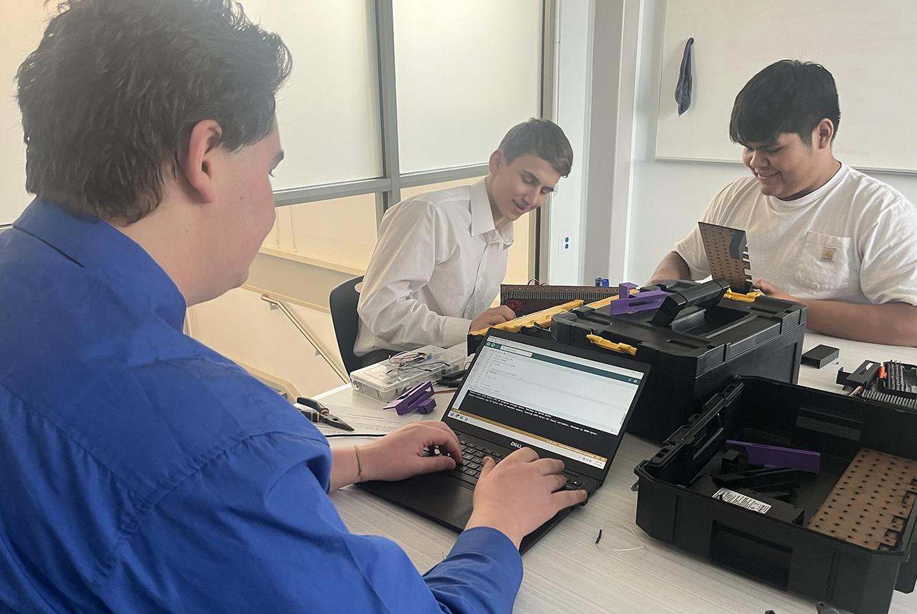 3 students work on a project at the TSA Event.