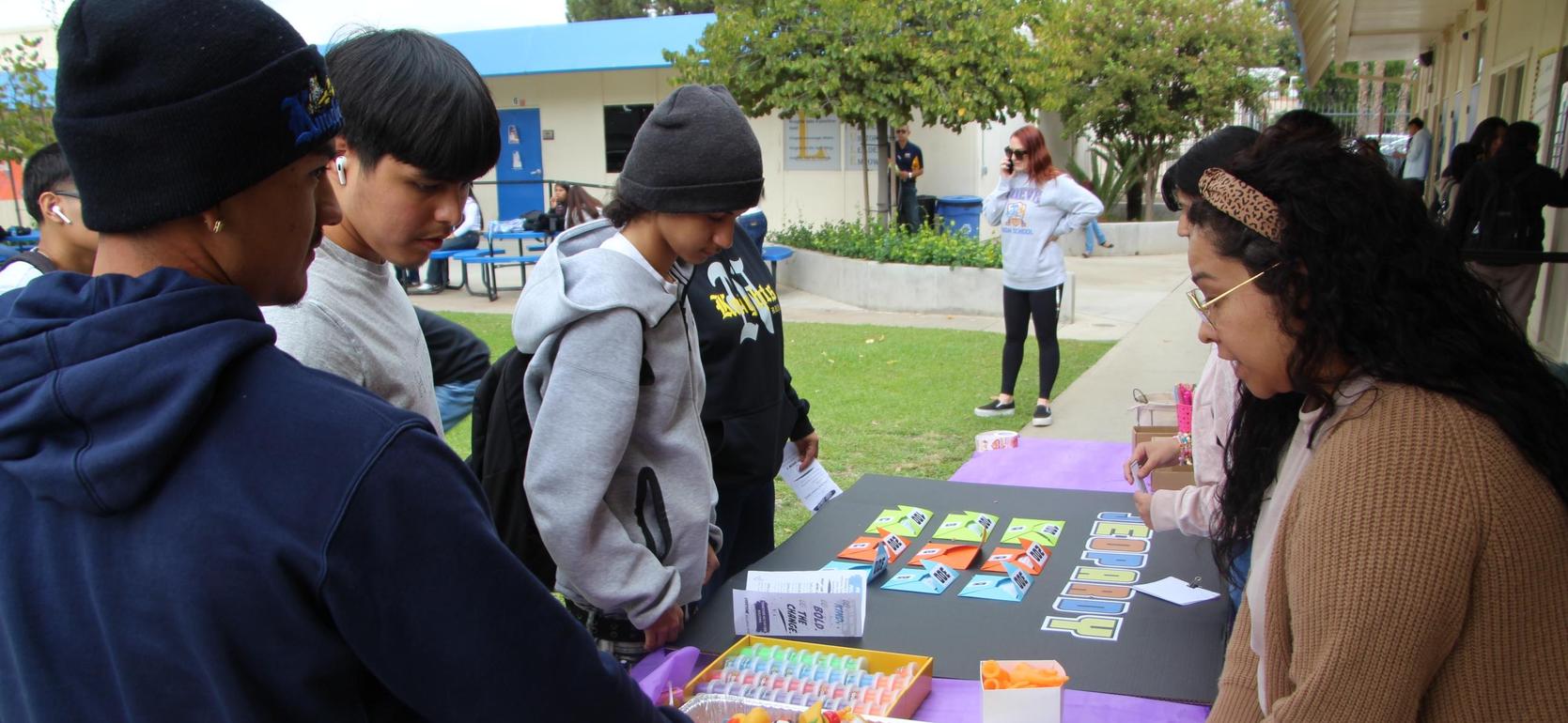 Students engaging at a table with games and colorful toys outdoors.