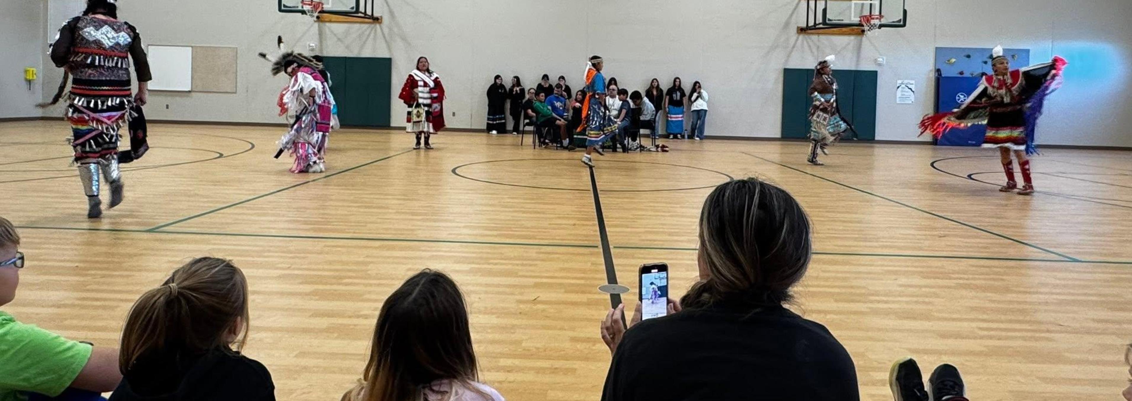 Kennedy Elementary Students Watching Pow Wow Presentation and Dancers.