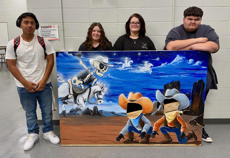 Art students pose with scene board they painted for Haunted Graves