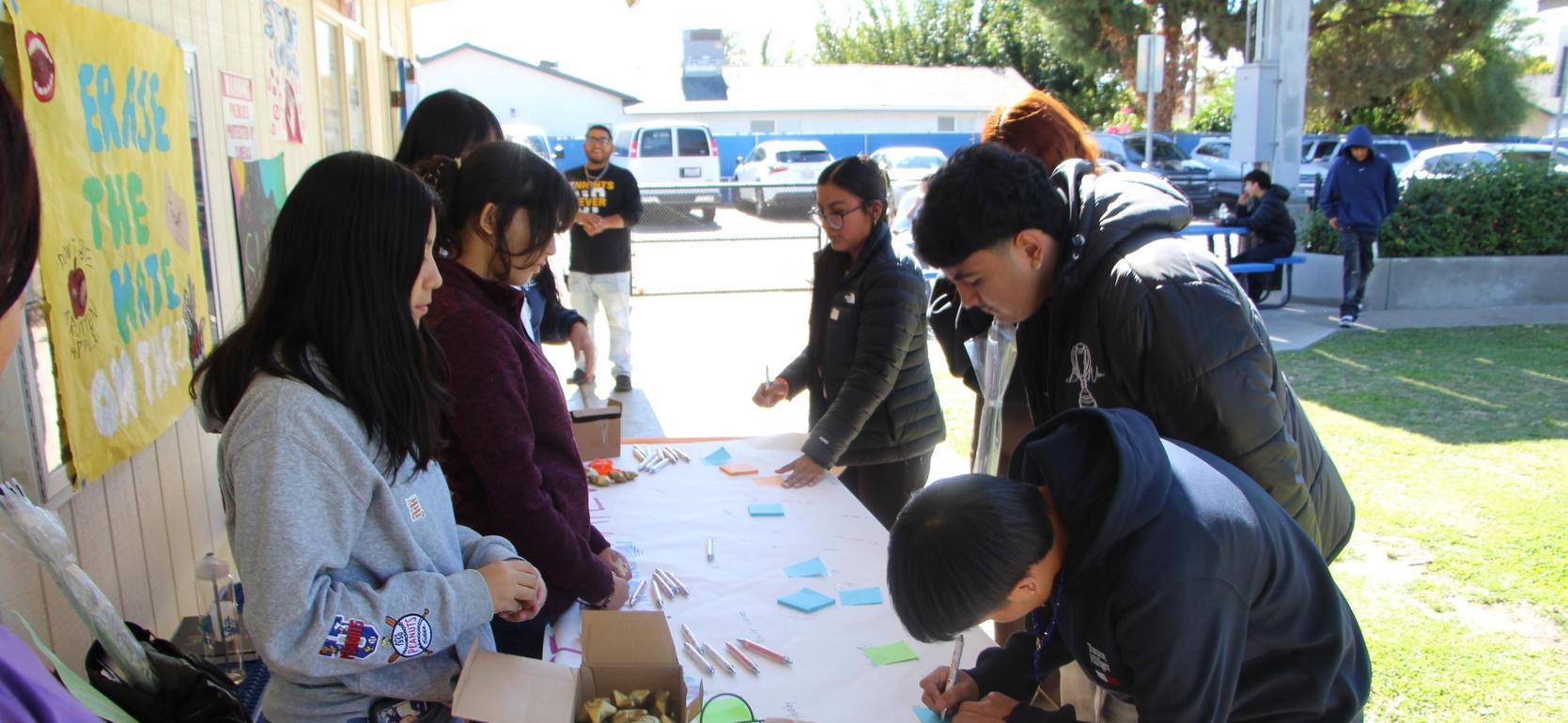 A group of students participating in an outdoor activity at a table.