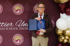 La Serna High teacher David Carter holds up his teacher of the year plaque from whittier union.
