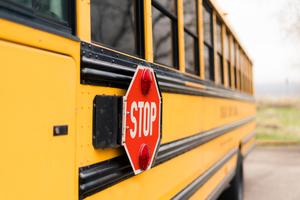 The side of a school bus is shown, with the focus on the stop arm, which is extended to make drivers stop for students entering or exiting the bus.