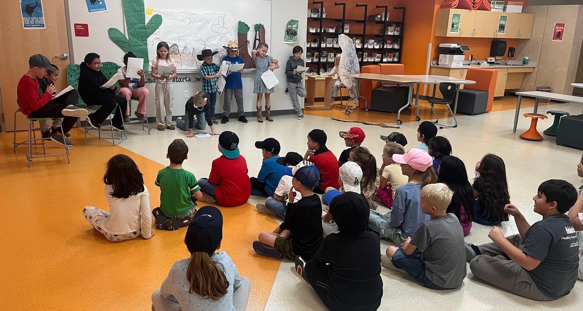 Students engage in a classroom performance while others watch attentively.