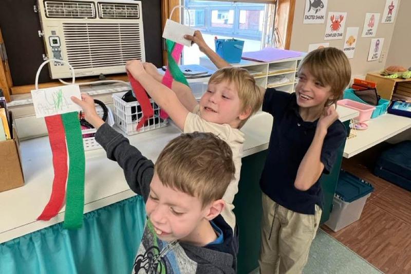 Students hold their Breeze Buddies in front of the air conditioner