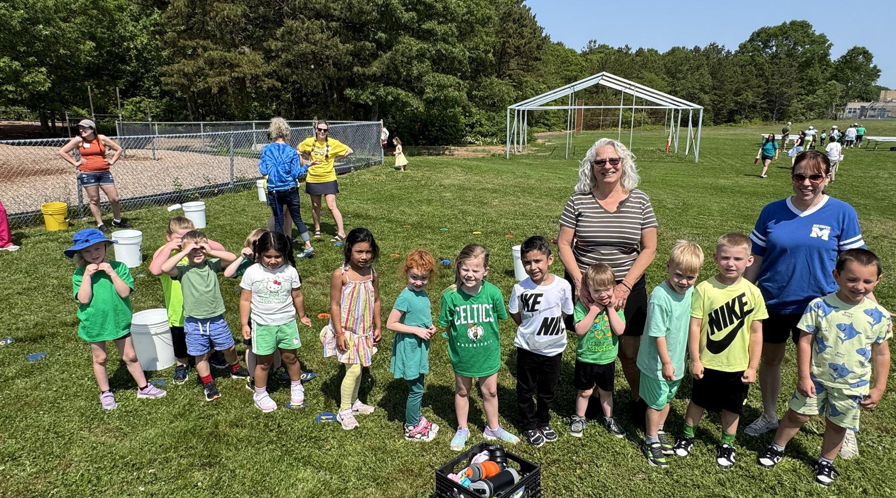 Children in colorful outfits participate in outdoor activities on a sunny day.