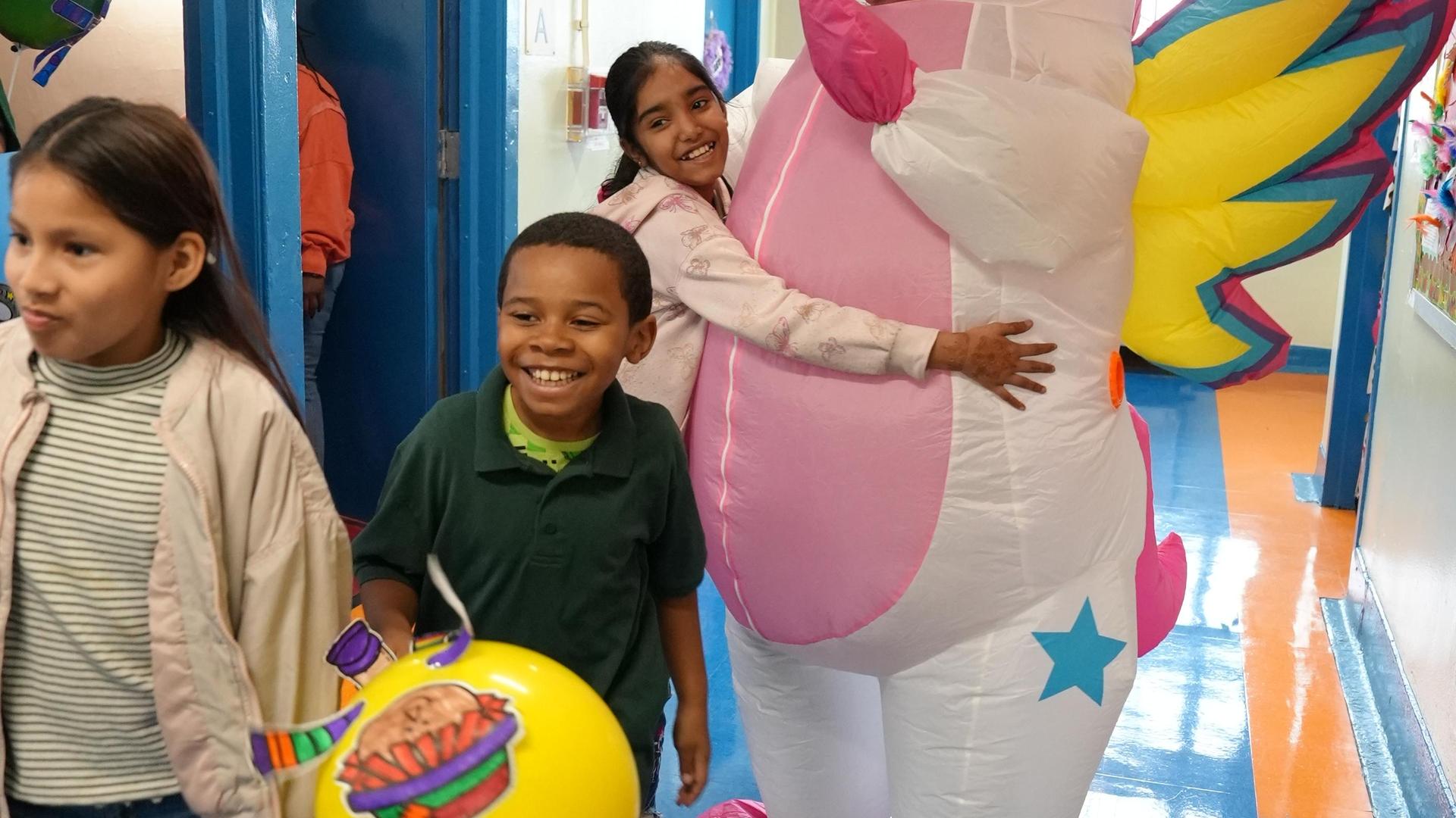 Children in a hallway with an inflatable unicorn.