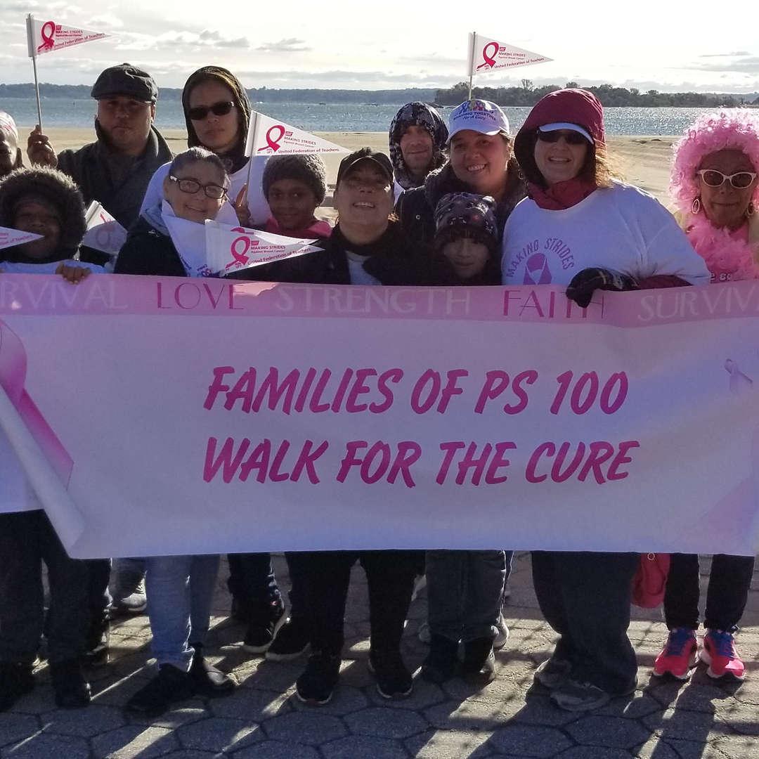 Group of people holding a banner for a charity walk by a waterfront.