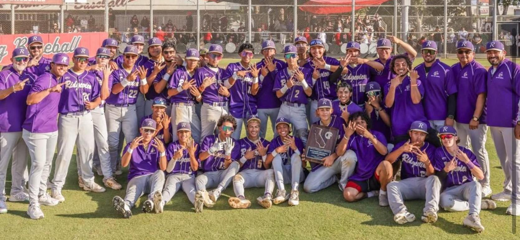 Baseball team celebrating a victory, posing with a trophy on the field.
