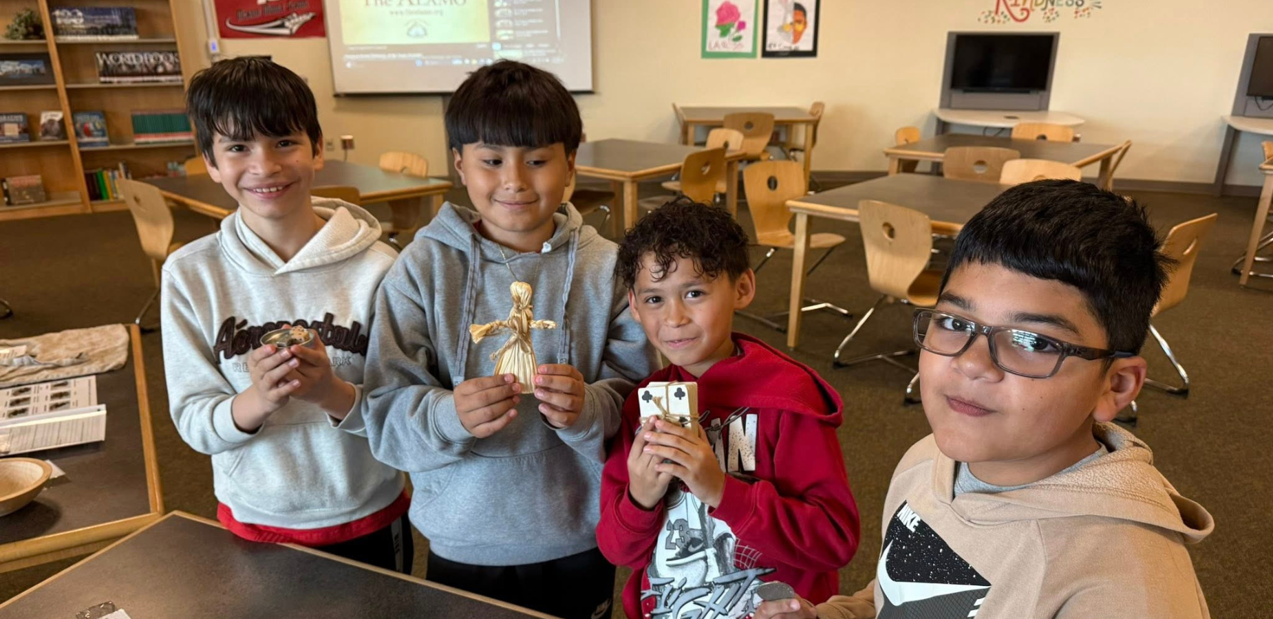 four boys holding historical artifacts at table