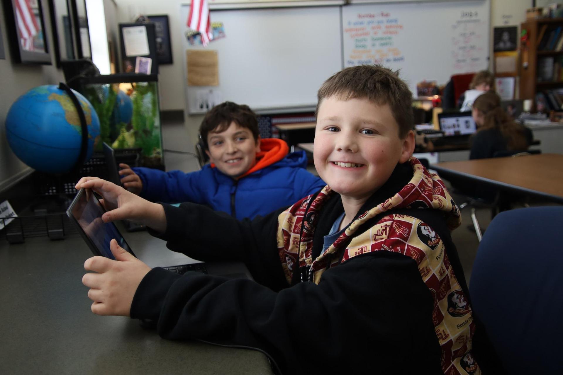 two middle school boys smiling at camera in the classroom