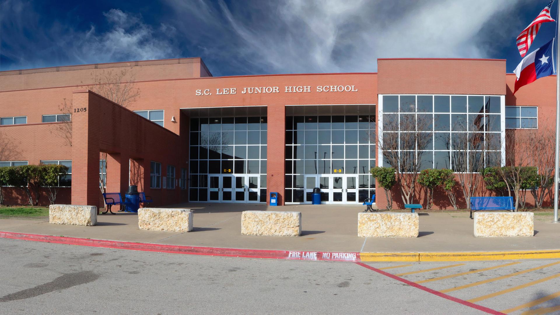 Exterior view of S.C. Lee Junior High School with flags and clear sky.