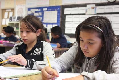 two students writing at a table