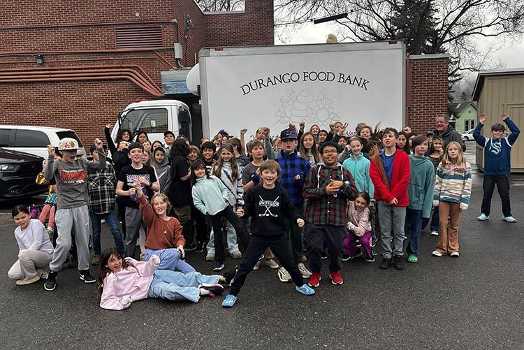 A large group of fifth-grade students stand in front of a box truck that reads Durango Food Bank.