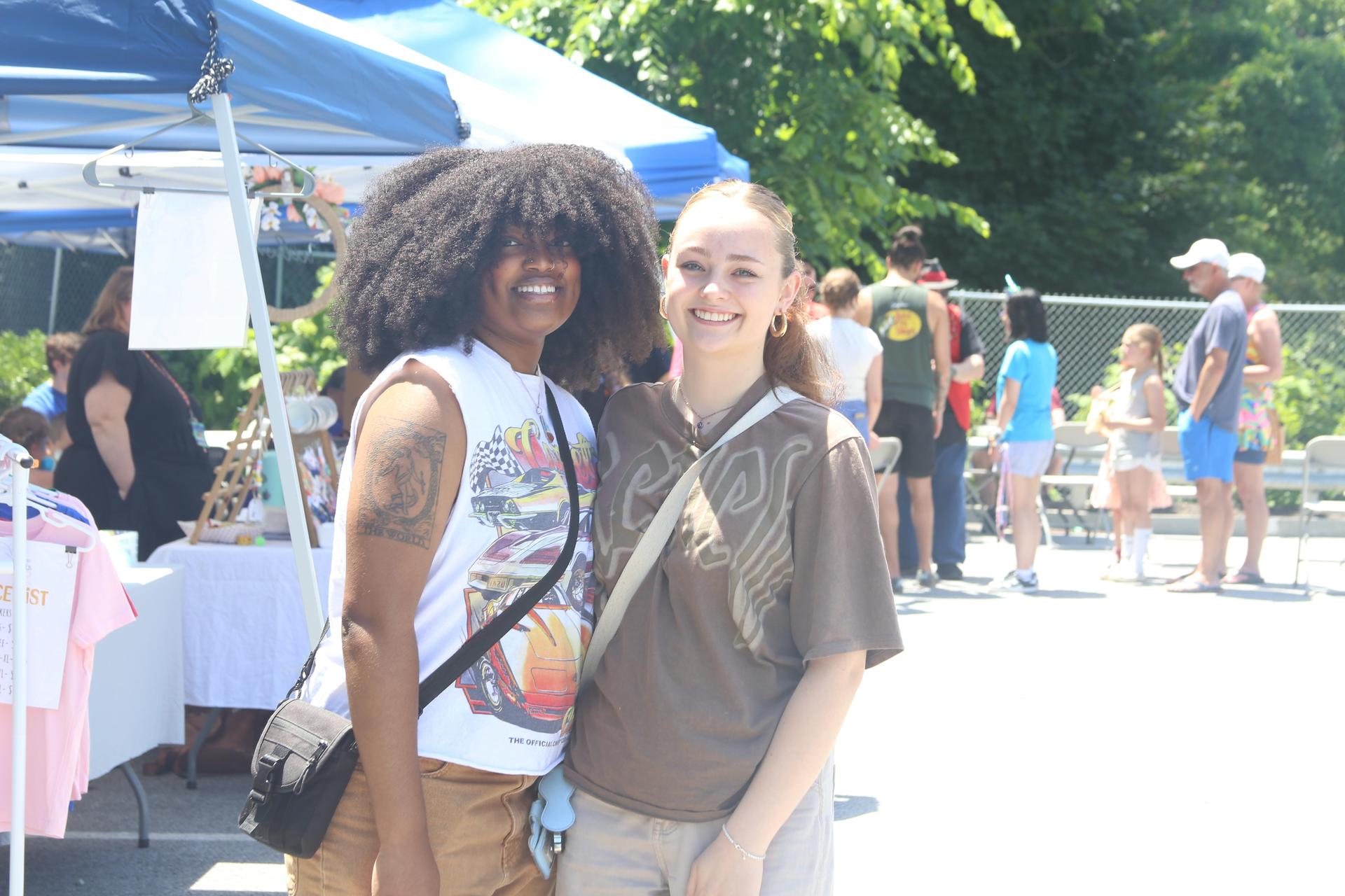 Two friends standing next to each other smiling.