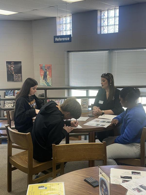 Students at a table talking with extension officer.