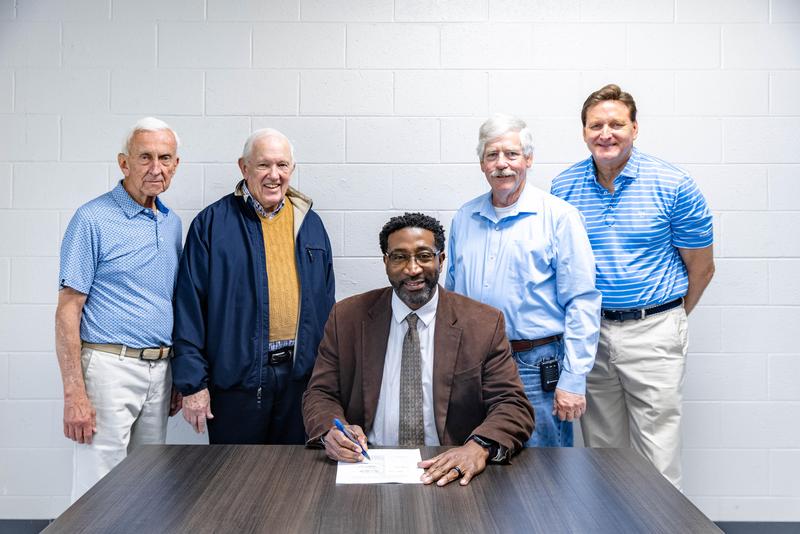 men around a table signing a contract