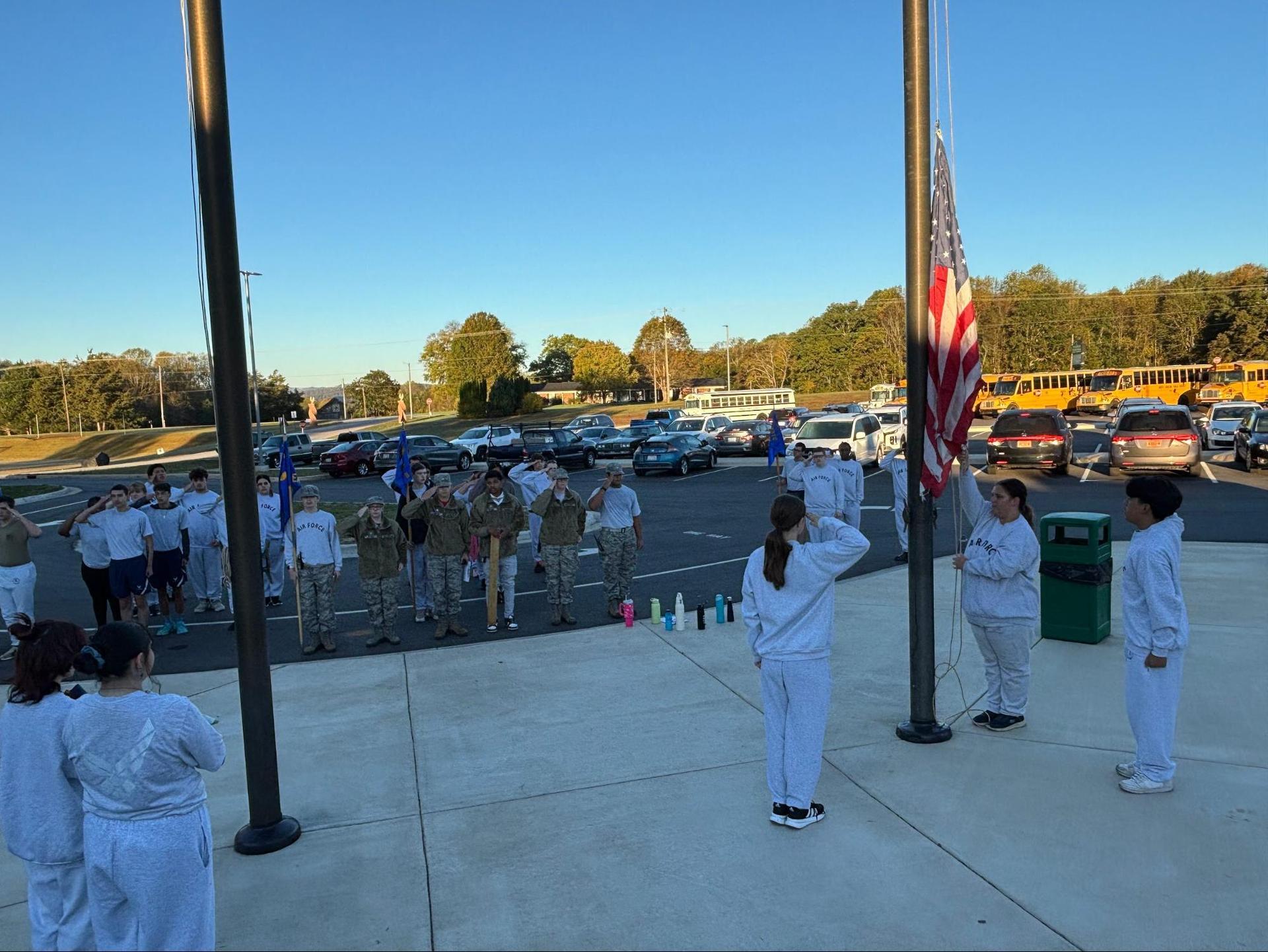 Students salute the flag during a ceremony outside a school.