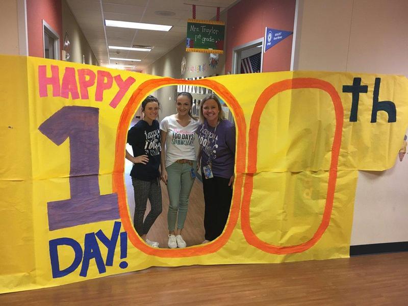 Adults standing behind 100 Days of School sign