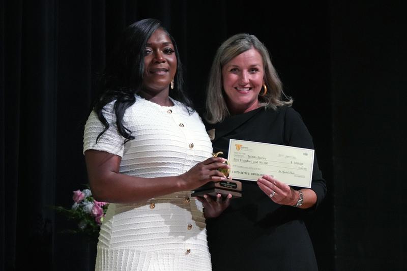 Telitita Burley accepts the award and check from Dr. Rhodes