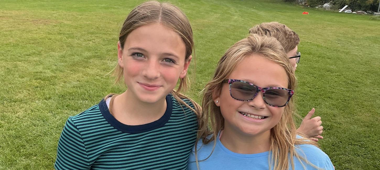 Two students smile in a field