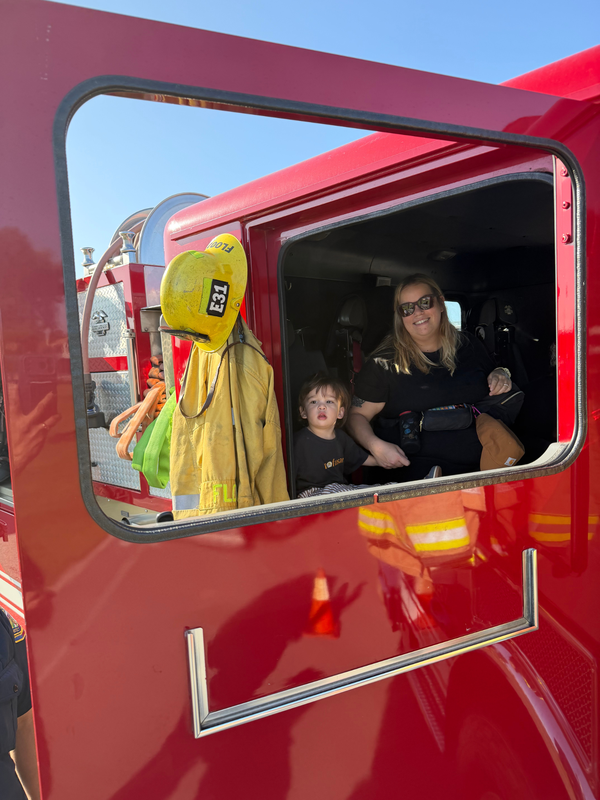 A woman and child inside a fire truck, smiling and enjoying the moment.