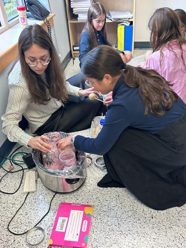 Mrs. Storch helps a student dip her cake pop in chocolate.