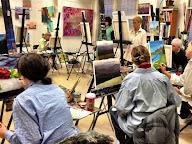 A group of painters working at easels in an art studio.
