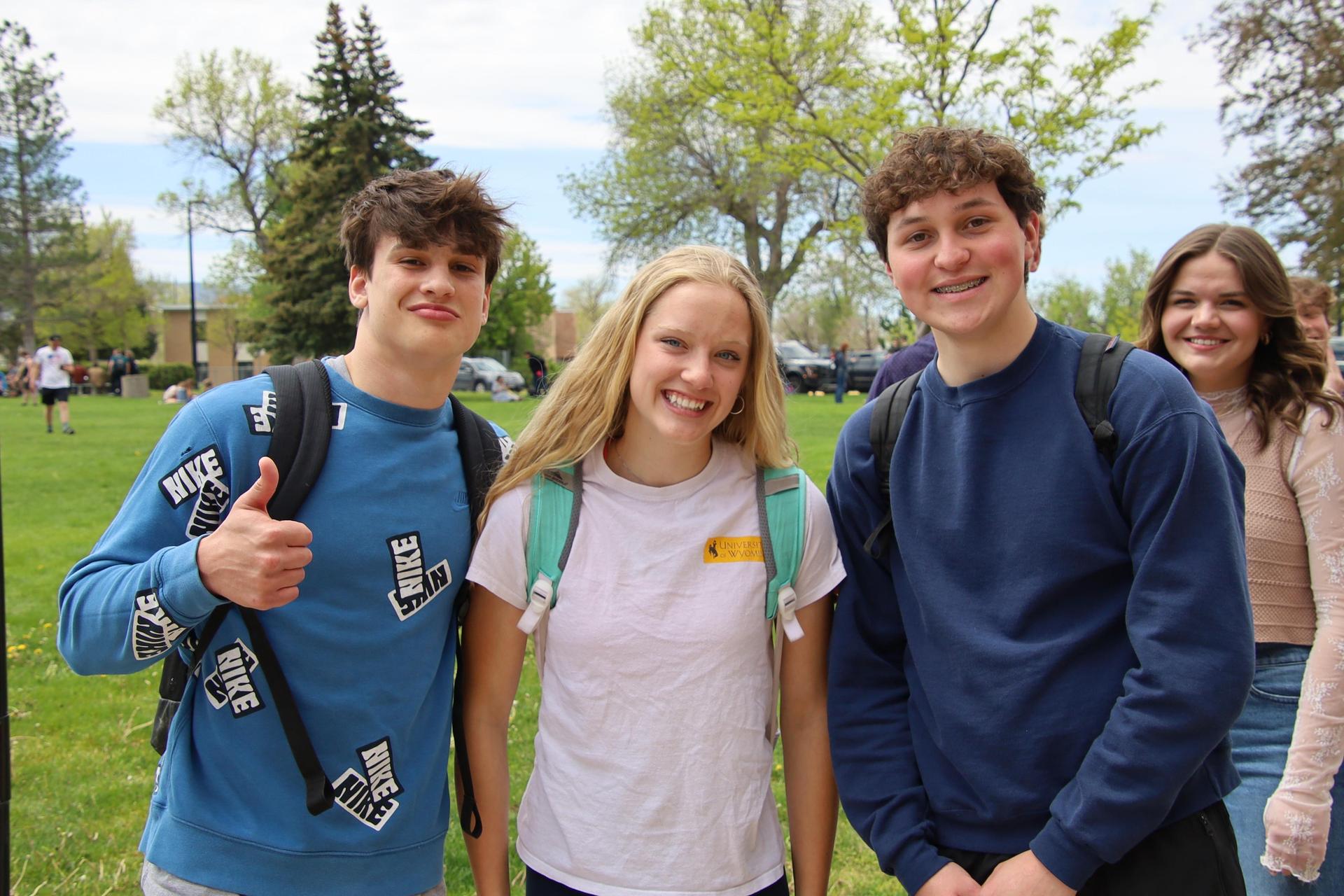 three high school students standing outside smiling for the camera