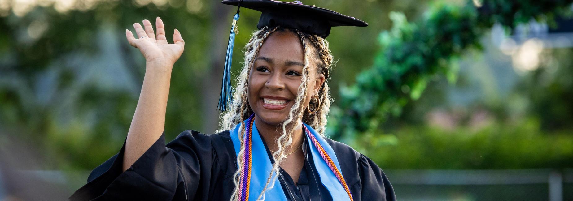 A graduate waves to the crowd before getting diploma