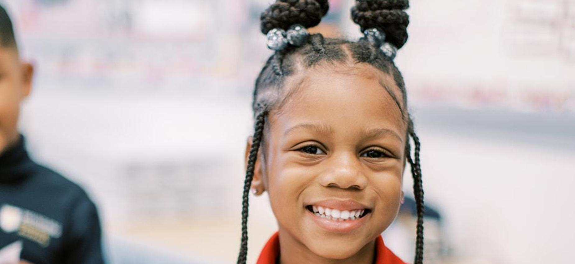 Smiling student in a red Founders polo in her classroom