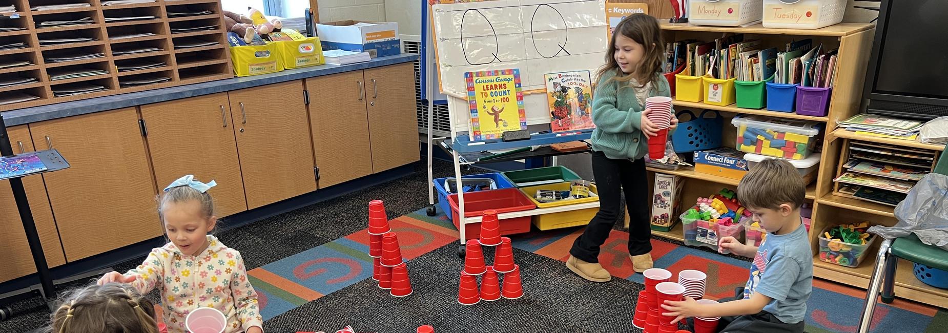 4 students in classroom stacking red cups