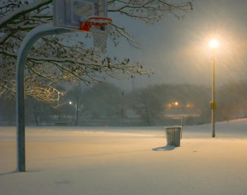 Outdoor view of school basketball court with snow covering the ground.