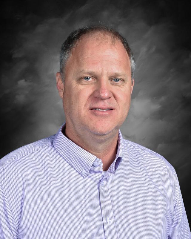 Middle-aged man in a dress shirt with a gray background.