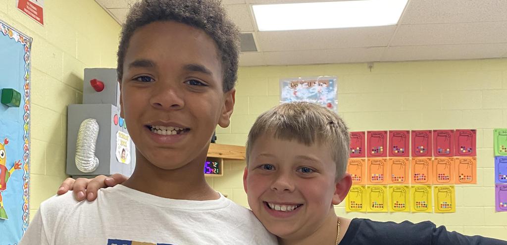 Two boys pose happily together in a classroom setting.