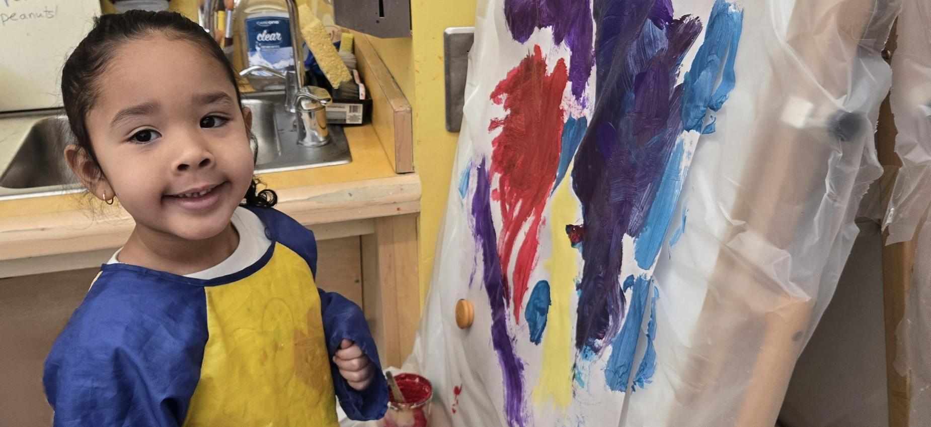 student using a paint brush and easel to paint