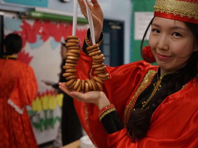 Person in traditional attire holds a necklace made of cookie-like rings.