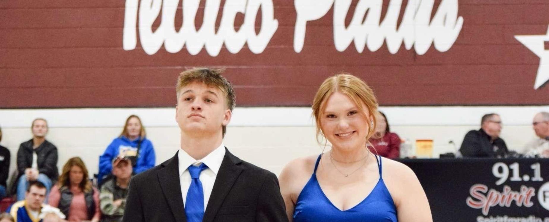 Pair in formal attire holding hands on a basketball court, featuring a rose.